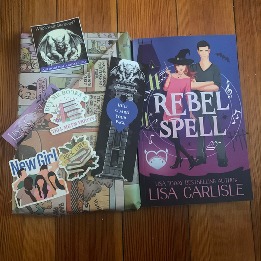 A book titled 'Rebel Spell' and one wrapped with stickers on a wooden surface