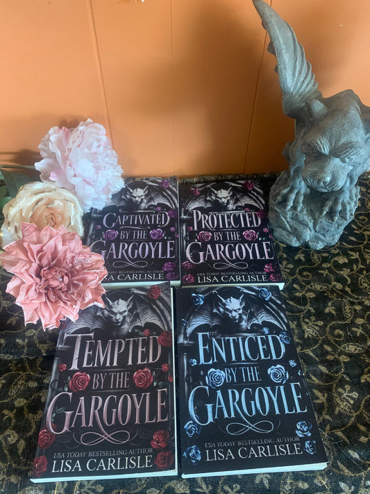 Four books titled 'Captivated by the Gargoyle', 'Protected by the Gargoyle', 'Tempted by the Gargoyle', and 'Enticed by the Gargoyle' by Lisa Carlisle on a textured surface with decorative flowers and a gargoyle statue.