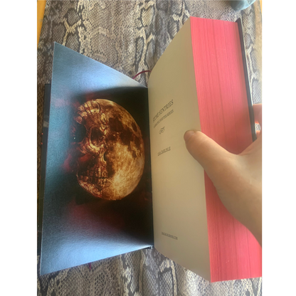 Book featuring a moon image held by a hand on a textured surface.