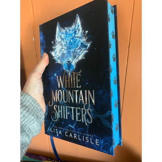 Book titled 'White Mountain Shifters' held by a hand against an orange background