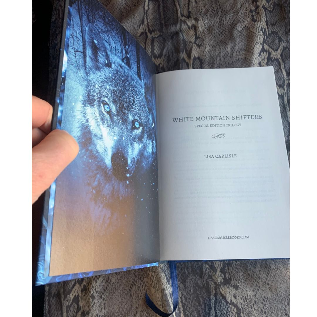 Open book with a wolf illustration on the cover held by a hand.